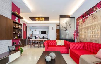 Modern living room with red sofa set and stylish wall décor in a 3BHK flat.