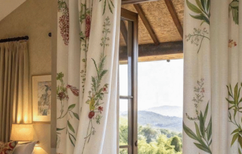 Bedroom with floral curtains opening to a scenic balcony view.