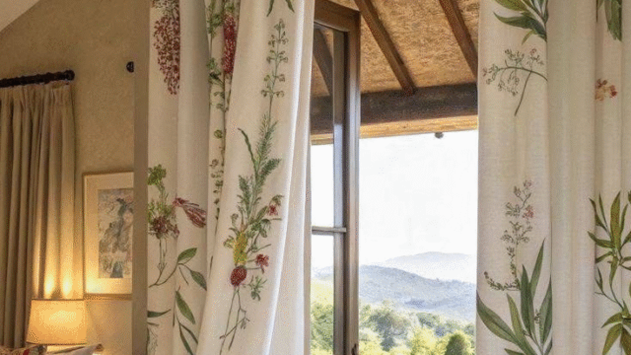 Bedroom with floral curtains opening to a scenic balcony view.